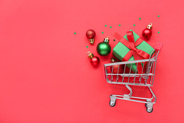 Wall Mural - Small shopping cart with Christmas decor on red background