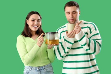 Canvas Print - Young couple with teapot and cup on green background