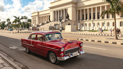 red classic car in front of historical building in the streets of havanna cuba