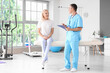 © Pixel-Shot - Male physiotherapist with clipboard and mature woman in rehabilitation center