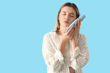 Sticker - Young woman with hot-water bottle suffering from tooth ache on blue background