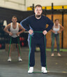 © JackF - Concentrated young bearded man in comfortable sportswear exercising with resistance band loop during intense group cross training in gym
