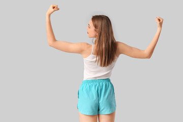 Poster - Sporty young woman on grey background, back view