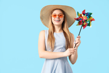 Canvas Print - Young woman in hat with toy windmill on blue background