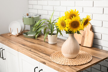 Vase with sunflowers near coffee machine on counter in kitchen. Closeup