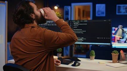 Remote software developer arriving in personal office at home, starting job shift with cup of coffee. Teleworker enjoying hot beverage while writing lines of code on computer, camera B