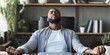 © kwanchaift - Entrepreneur engaging in deep breathing exercises at a home office desk combating work stress with mindfulness techniques