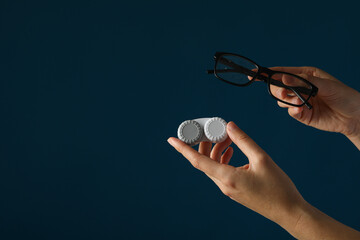 Wall Mural - Glasses and a container for contact lenses in hands