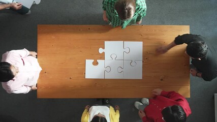 Wall Mural - Top view of business man gathering last piece of jigsaw to complete puzzle. Group of diverse team working together to solve the puzzle while putting hands together and clapping hands. Convocation.