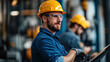 © khonkangrua - Confident construction worker wearing a yellow hard hat and safety glasses, standing in an industrial setting, ready for the job.
