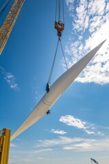 Wall Mural - A wind turbine tower section is lifted by a crane. Other construction equipment and turbines are in view