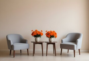 Two gray armchairs with a small wooden table between them, a vase with orange flowers on the table, against a plain beige wall background.