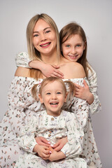 Wall Mural - Family portrait on a white background. Portrait of young mother and daughter. Happy mother and two children