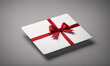 © Miklos - A white gift card with a red ribbon and bow lies on a gray surface