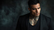 © Keitma - Trendy hispanic male model, with short hair, wearing plain black t-shirt and black blazer jacket over the top, tattoos and jewelry , man with bad boy vibes over dark foggy background