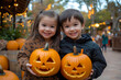 © FranKissStudio - Two children holding carved pumpkins smiling at halloween event