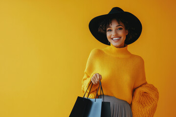 Wall Mural - A happy young Indian woman in a yellow sweater, black hat, and grey trousers, holding shopping bags and laughing