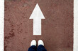 © YuTphotograph - White straight arrow sign and white shoes. The concept of straight direction. The journey concept