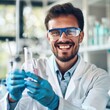 © RDO - A scientist in a lab coat holding a test tube with a bright smile, indicating a successful experiment in a laboratory.