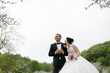 © Vasil - A bride and groom are standing in a field with a beautiful view of the sky. The bride is wearing a white dress and the groom is wearing a suit. They are both smiling and looking at the camera
