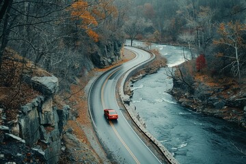 Wall Mural - a car driving down a winding road next to a river