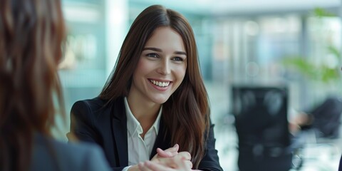 Wall Mural - A professional woman in her late thirties, smiling and shaking hands with an employee at the table during a job interview in an office.