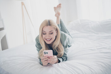 Wall Mural - Full body portrait of nice young lady lay bed use smart phone pajama white interior bedroom flat indoors