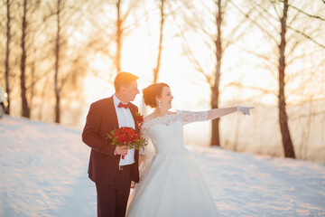 A bride and groom are pointing to the sky. The bride is wearing a white dress and the groom is wearing a suit