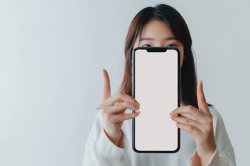 Wall Mural - Beautiful Asian woman holding smartphone mockup of blank screen and shows ok sign on grey background Beautiful Asian woman holding smartphone mockup of blank screen and shows ok sign on grey backgroun