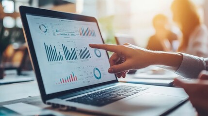 Leinwandbilder - Hand pointing closely at detailed data and analytical graphs displayed on a laptop screen during a business meeting, emphasizing critical information analysis.