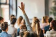 © alisaaa - Back view of a woman wants to ask a question on a seminar. Rear view of casual businesswoman raising her hand to ask the question on education event in a board room.