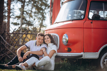 Beautiful happy couple in love man and woman, at the red bus trailer