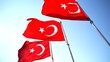 © Bankerok - Close up of the row of Turkey national flags on high flagpole waving in the wind against a clear blue sky