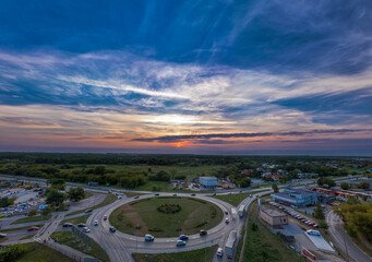 a breathtaking aerial shot of a roundabout captured at sunset, with a vibrant sky full of colorful c