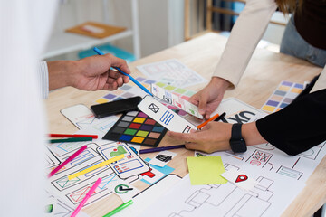 Wall Mural - creative team collaborating on ux ui design with colorful prototypes and wireframes on a wooden desk