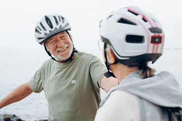 Sticker - Senior couple riding bikes together in rocky beach enjoying outdoor. Active mature people talking and hugging each others. Bicycle lifestyle concept, having fun