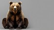 © sarun - A single brown bear sitting against a solid gray background, highlighting its strength and power.