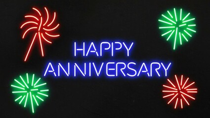 Wall Mural - festive neon backlit style of the word happy anniversary with neon fireworks on a black grainy background