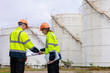 © SHUTTER DIN - Engineer survey team wear uniform and helmet stand workplace checking blueprint project  talk and meet plan work  oil storage tank backgrounds.