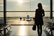 © Olya Ivanova - Young woman, silhouette at the airport waiting for a plane, looking at the plane taking off, photo. Travel, flight, vacation, tour.
