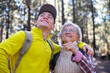 © luciano - Couple of happy grandmother and young grandson in trekking day in the forest looking the nature, young and old people enjoying together outdoors excursion