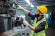 © eakgrungenerd - Man technician worker using tablet control setting up operating electric drill machinery of lathe metal factory industrial. Male worker wear yellow hardhat controlling iron drilling machine.