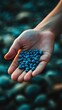 © kinara art design - A hand holding a collection of small blue stones against a blurred background.