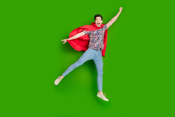 Canvas Print - Full size photo of overjoyed guy dressed print shirt red cloak fly to empty space raising fist up isolated on green color background