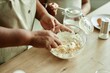 © Seventyfour - Close up on hands of senior Black woman stirring baking powder and eggs in glass bowl for making pancakes cooking together with granddaughter on wooden kitchen counter, copy space
