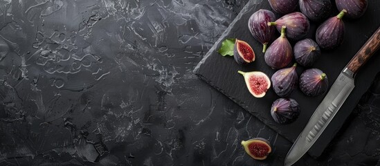 Poster - Figs on a dark stone table with a knife viewed from above Ripe figs on a black surface or background with copy space