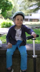 Boy sitting on a bench with a helmet, enjoying a sunny day in the park, representing the joy and freedom of childhood in a safe, outdoor environment