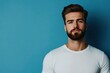 © Nico - A Man with a Beard Wearing a White T-Shirt Against a Blue Background