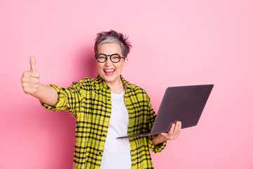 Wall Mural - Photo of nice aged woman thumb up laptop checkered shirt isolated on pink color background