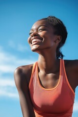 Black woman stands outdoors in summer with blue sky background and fluffy white clouds. She wears vibrant orange tank top and has high ponytail hairstyle, smiling directly at camera.